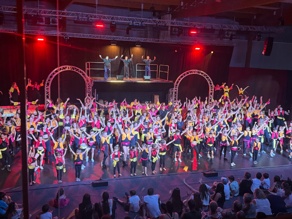 Final du gala de danse avec tout les participants sur scène, la structure scénique, des lumière et le public